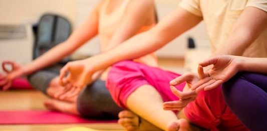 Group of people sitting in lotus position in the fitness studio