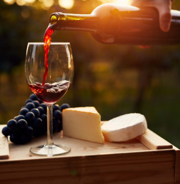 Pouring red wine into the glass in the vineyard at sunset