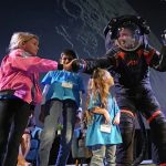 Imagem: O engenheiro-chefe da Axiom Space, Jim Stein, cumprimenta crianças durante uma demonstração dos trajes/Photo/David J. Phillip