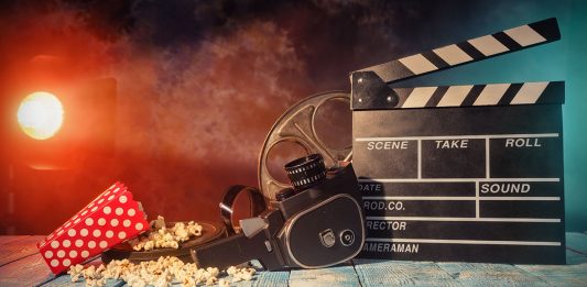 Retro film production accessories placed on wooden planks. Concept of film-making. Smoke effect with spot light on background