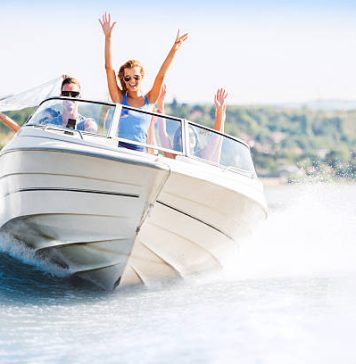 Group of young people with raised hands enjoying in a speedboat ride.